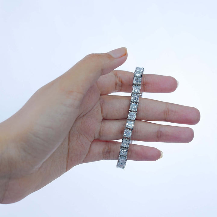 Hand holding white gold bracelet with princess-cut lab-grown diamonds for detail view.