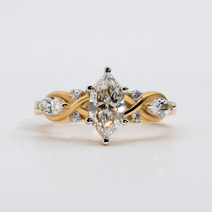 A gold engagement ring featuring a marquise-cut diamond at the center, set with prongs.