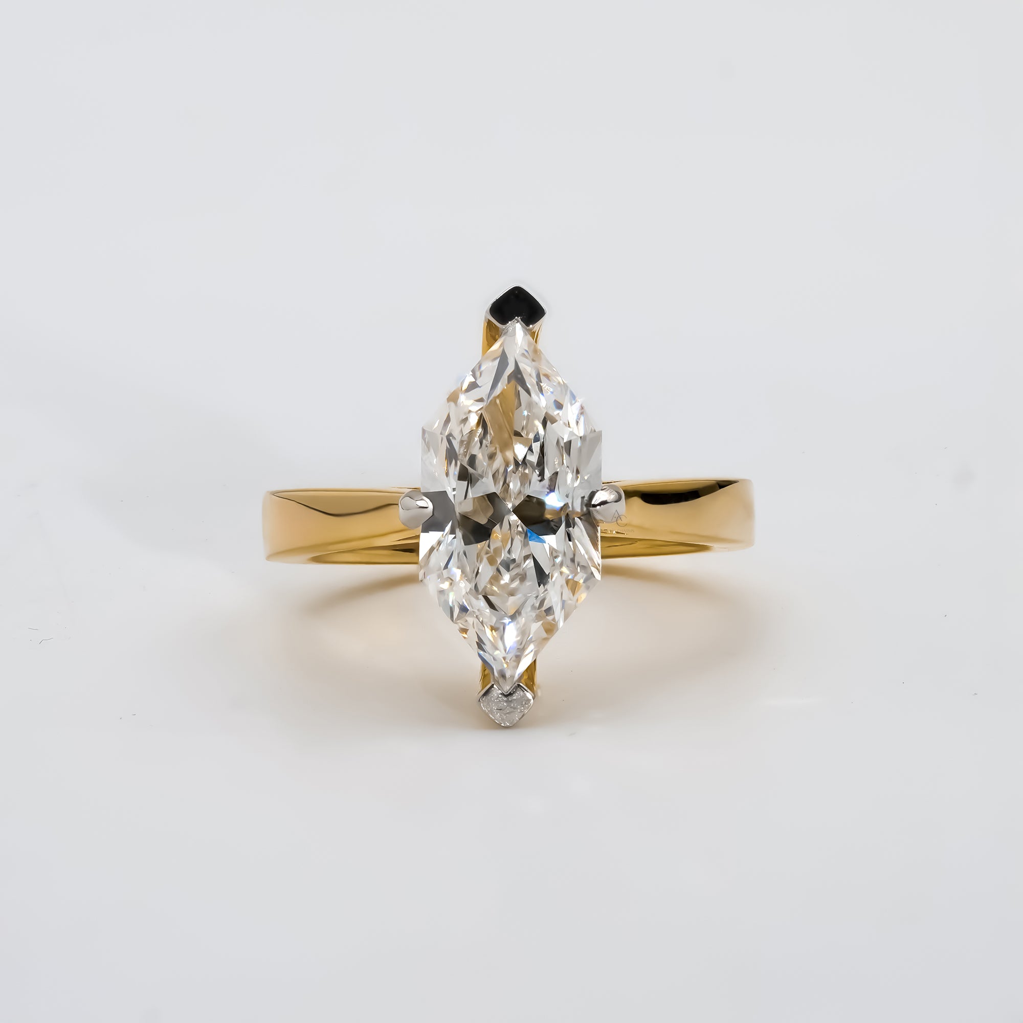 A yellow gold engagement ring featuring a marquise-cut diamond at the center, secured by six prongs. The diamond’s elongated shape adds brilliance and elegance to the simple, polished gold band.
