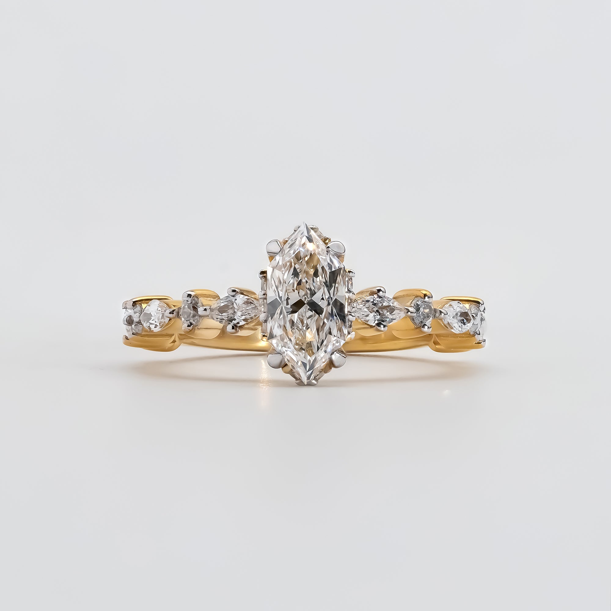 A gold engagement ring featuring a marquise-cut diamond at the center, held by six prongs.