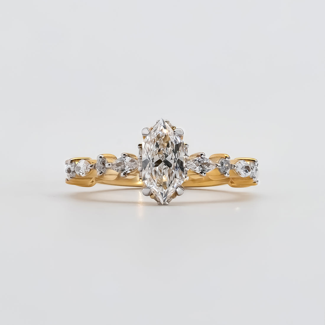 A gold engagement ring featuring a marquise-cut diamond at the center, held by six prongs.