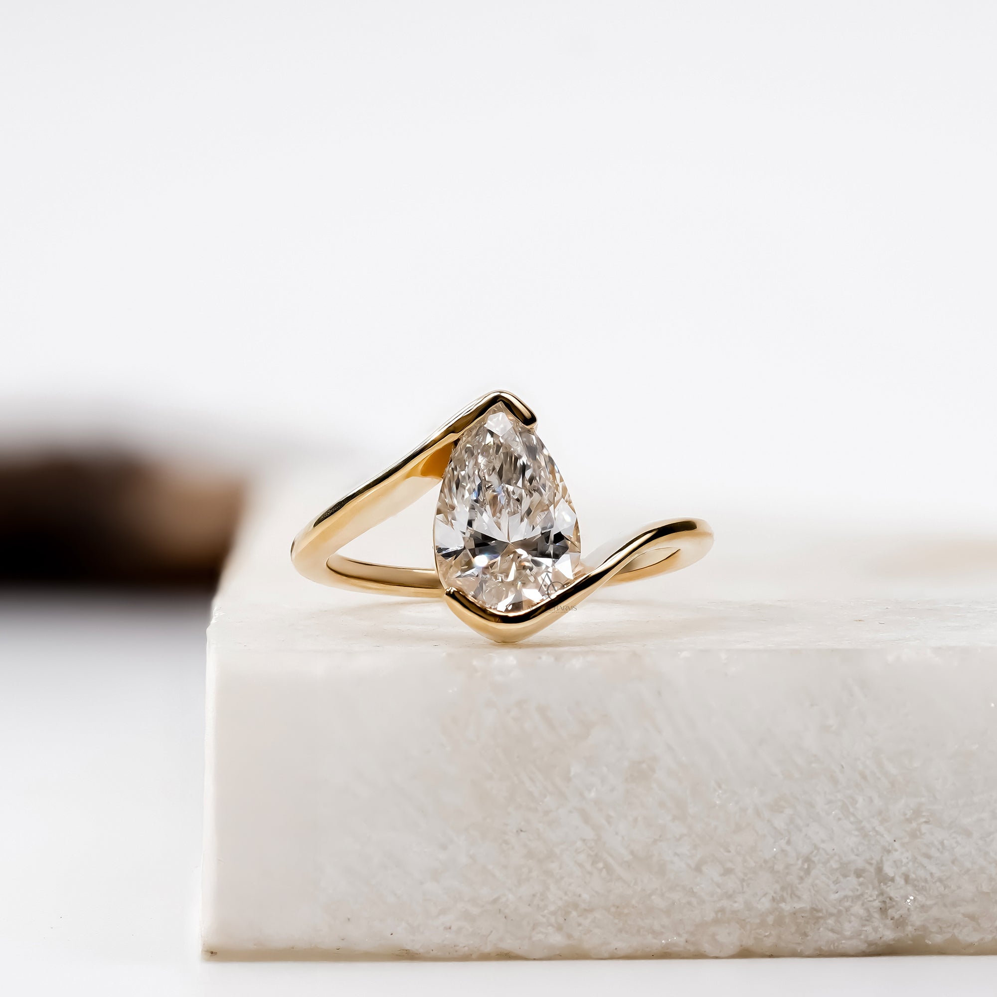 Modern engagement ring with a pear-cut diamond held in an open, flowing gold setting