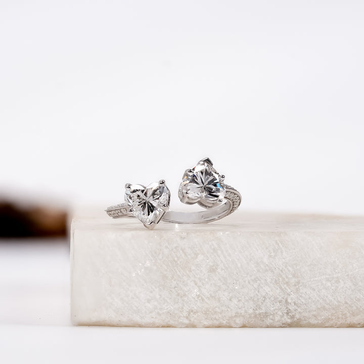 A silver ring featuring two heart-shaped clear gemstones