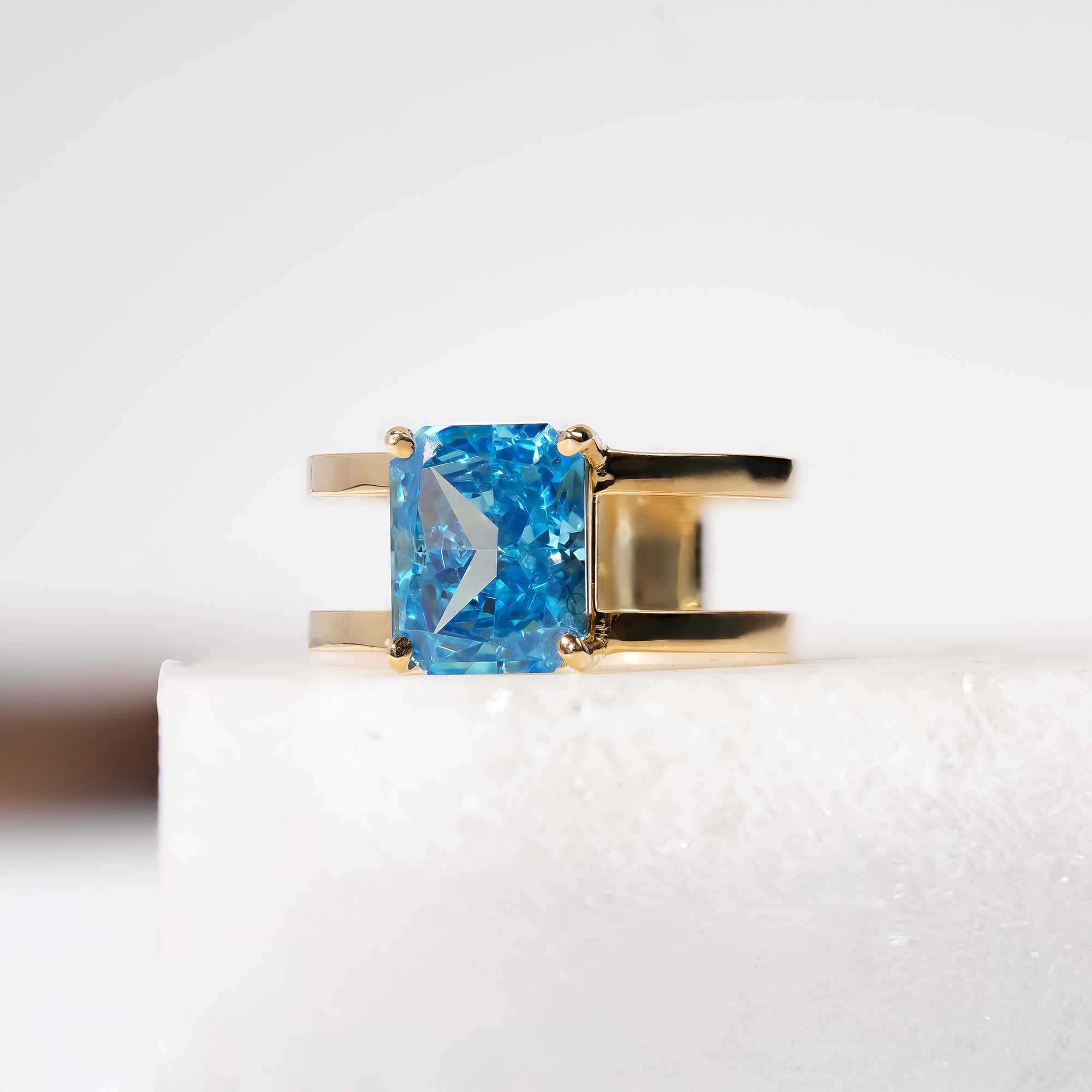 A gold band ring featuring a vivid blue rectangular gemstone.