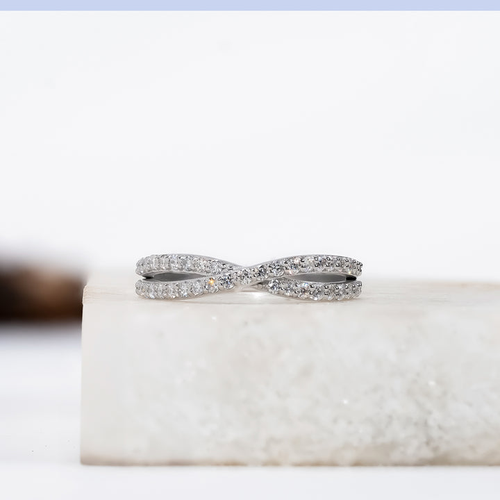 A silver infinity ring encrusted with small round diamonds