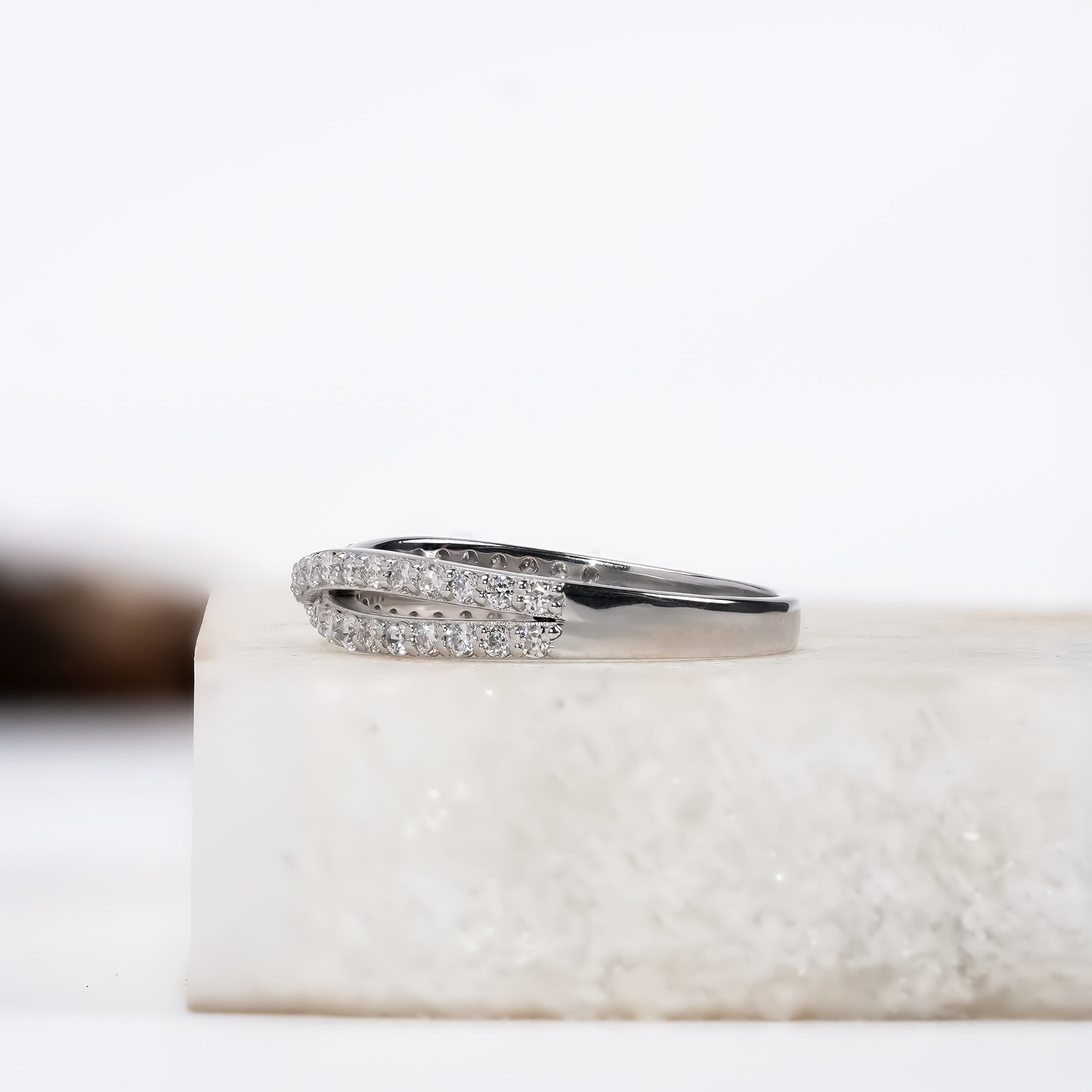 Elegant silver ring featuring a twisted infinity design with sparkling gemstones.