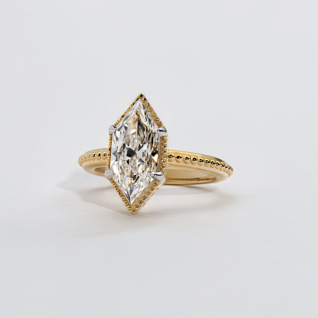 A marquise diamond solitaire ring in a textured yellow gold band.