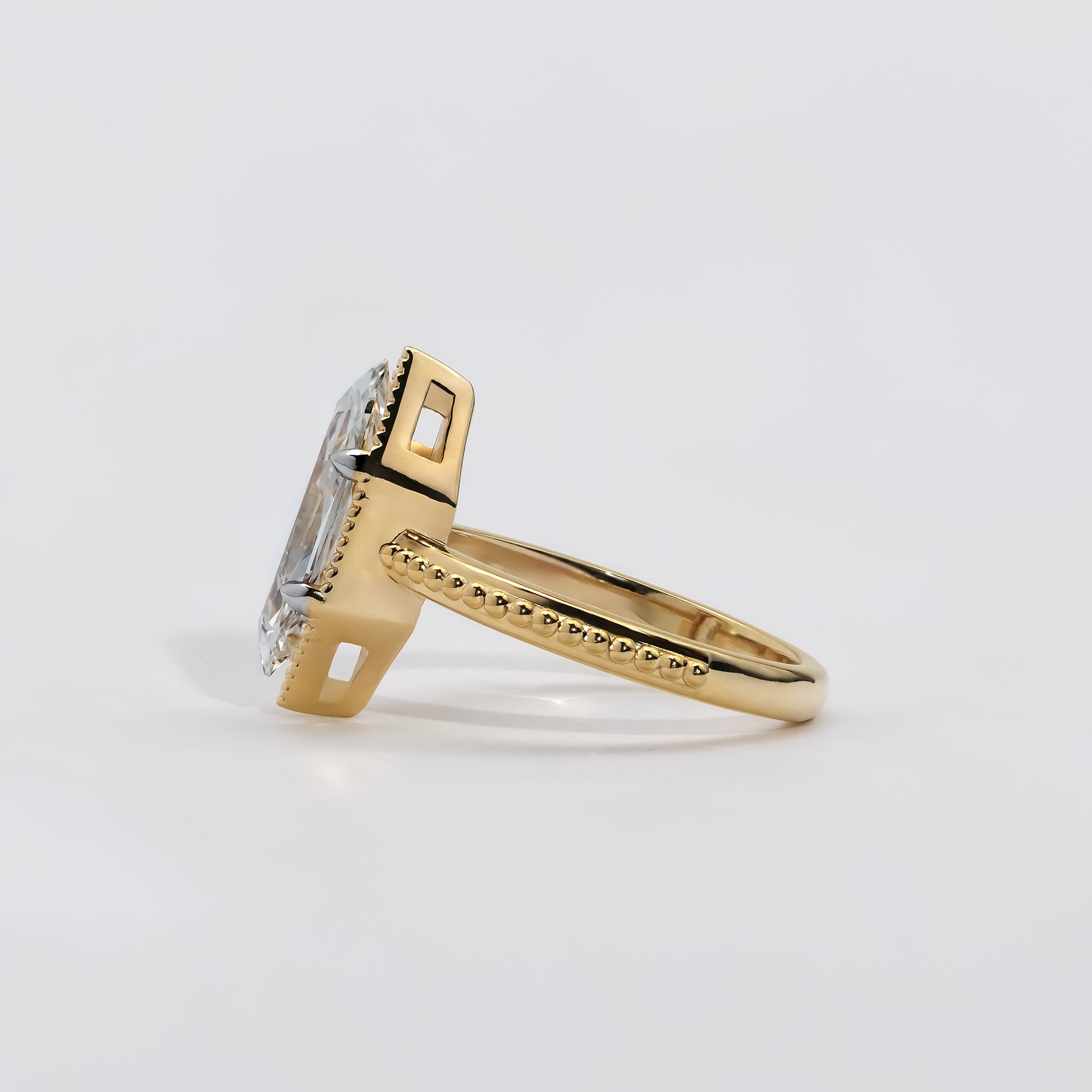 Elegant marquise-cut diamond ring in a milgrain-detailed yellow gold bezel setting.