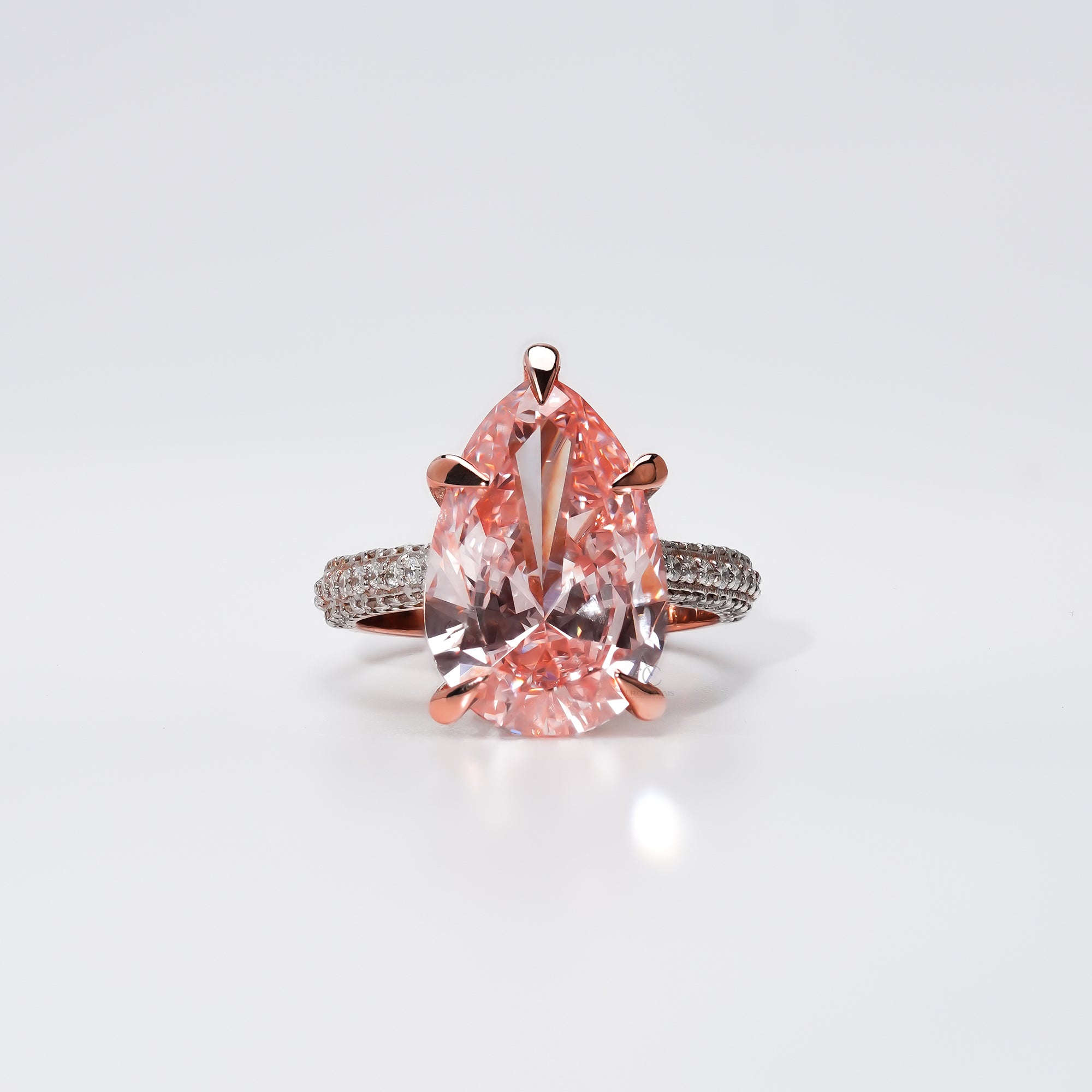 A pear-shaped pink gemstone ring set in rose gold, with a diamond-studded band that sparkles with delicate brilliance a perfect symbol of love and grace.