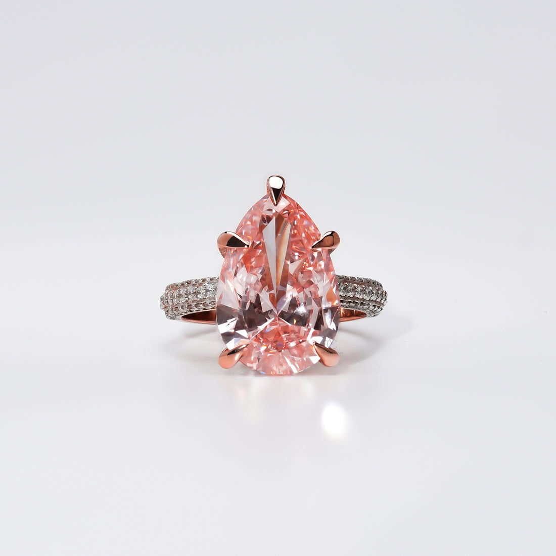 A pear-shaped pink gemstone ring set in rose gold, with a diamond-studded band that sparkles with delicate brilliance a perfect symbol of love and grace.