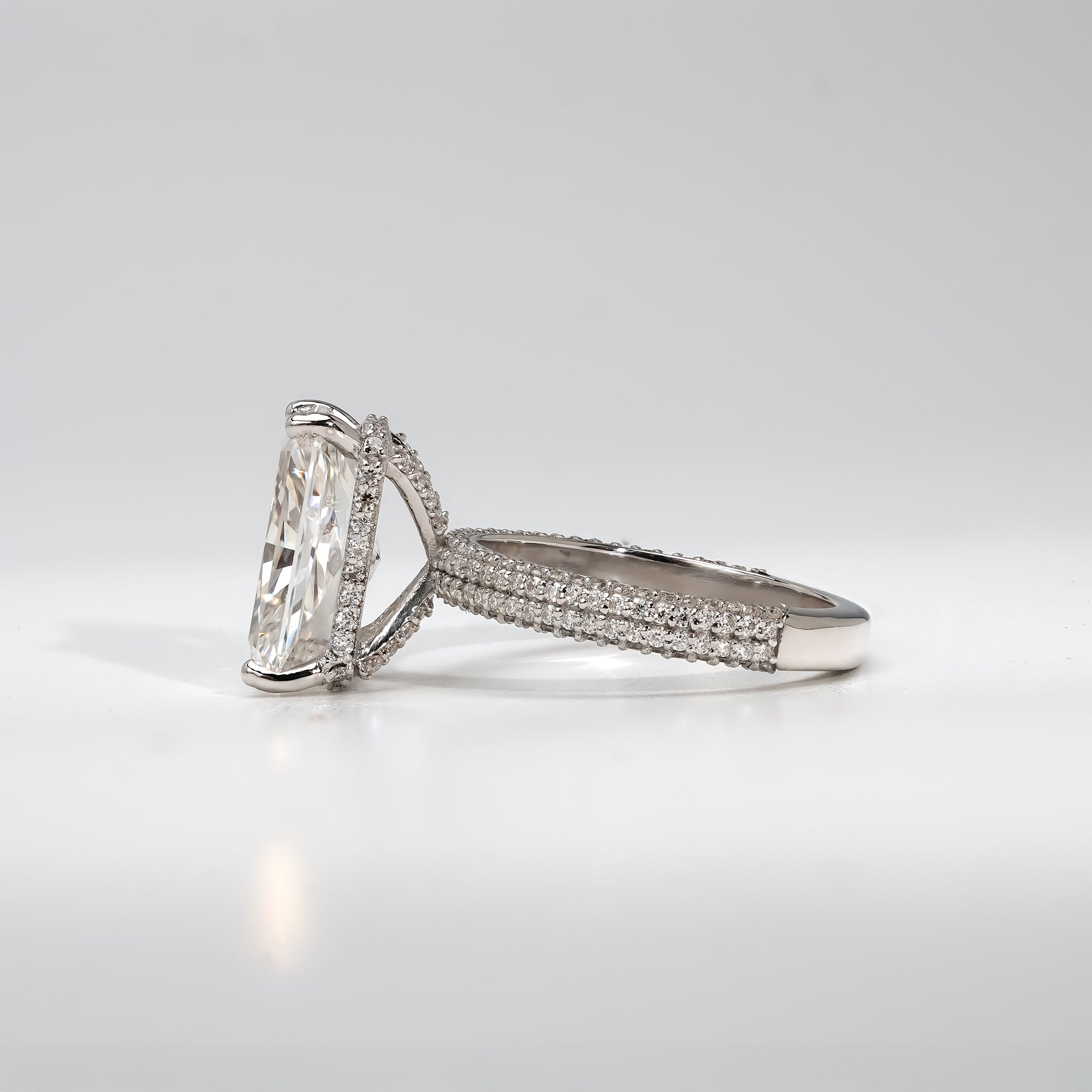 An elegant platinum ring with a radiant-cut center diamond and a triple pavé diamond band, symbolizing timeless love and refined beauty.