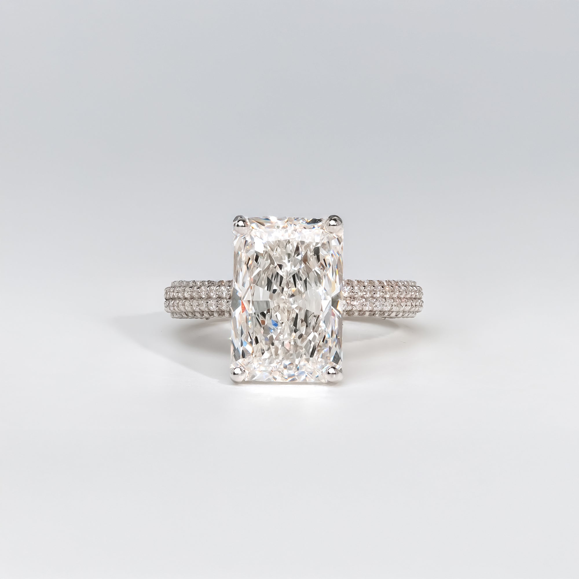 Radiant-cut diamond engagement ring in platinum with a triple-row pavé diamond band for a sophisticated and modern look.