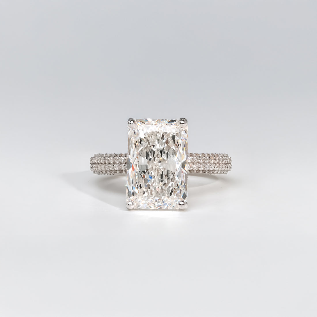 Radiant-cut diamond engagement ring in platinum with a triple-row pavé diamond band for a sophisticated and modern look.