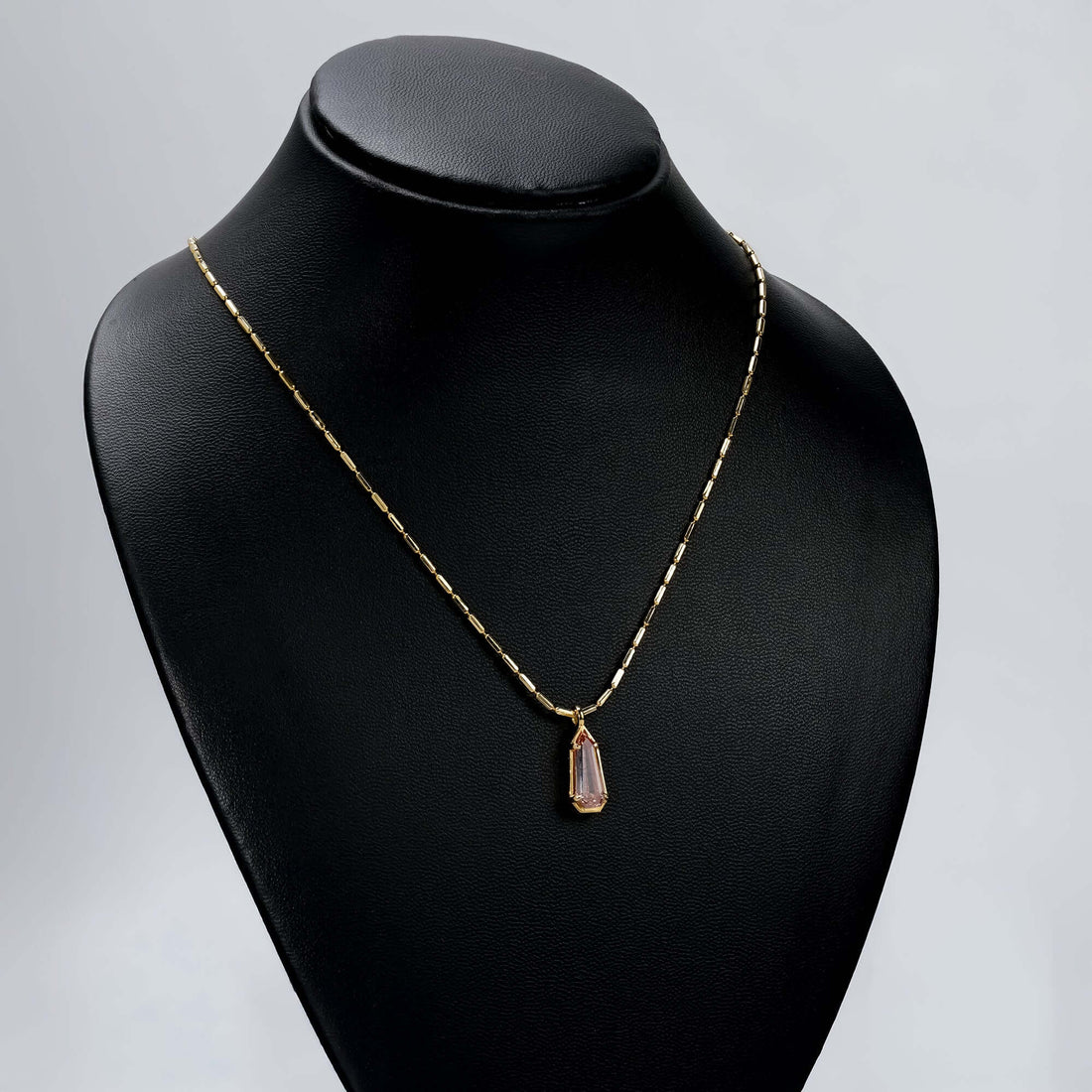 Gold necklace with pink gemstone pendant, featuring a faceted teardrop-cut stone in a minimalist, elegant design perfect for everyday wear or gifting.