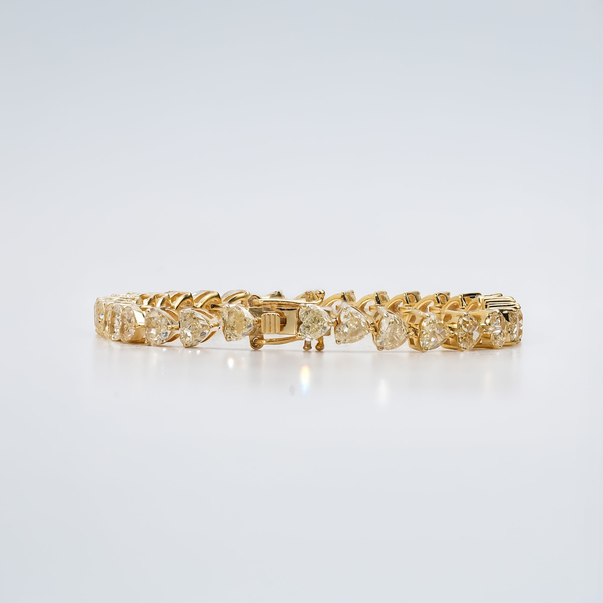 A stunning gold bracelet adorned with heart-cut diamonds, gracefully arranged in a seamless pattern that radiates timeless elegance and sophistication.