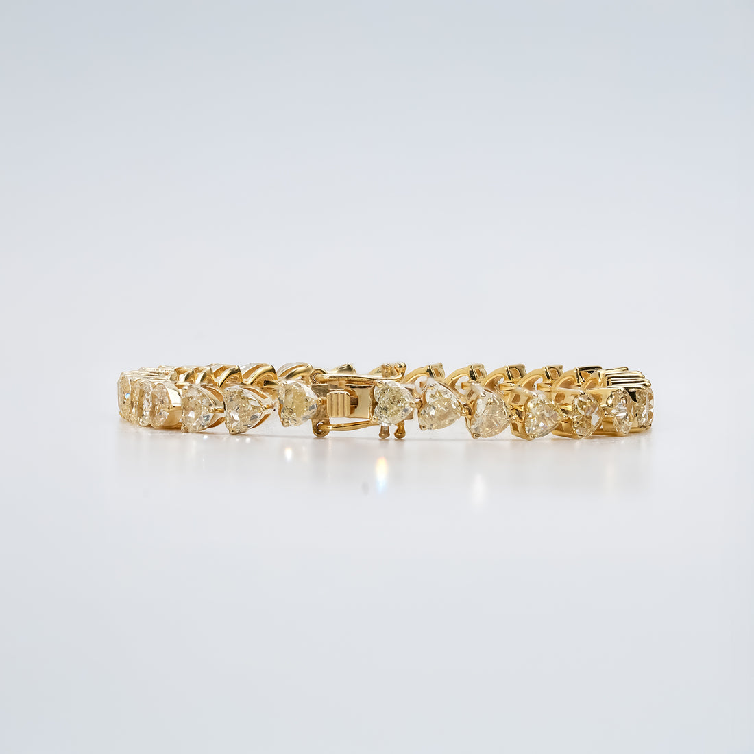 A stunning gold bracelet adorned with heart-cut diamonds, gracefully arranged in a seamless pattern that radiates timeless elegance and sophistication.