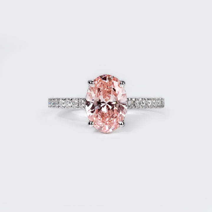 An oval-cut pink diamond ring set in a white gold band adorned with small pavé-set white diamonds.