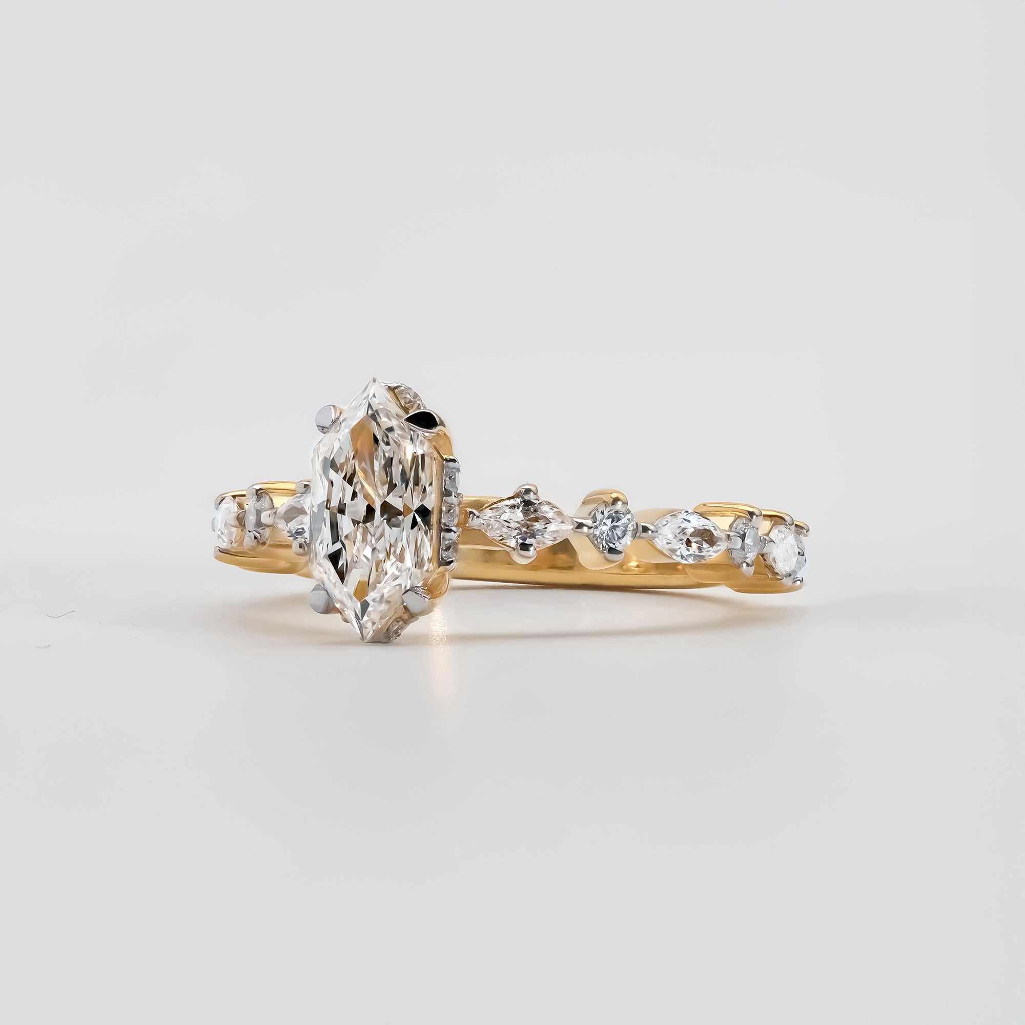 The band is adorned with alternating marquise and round-cut accent diamonds, creating an intricate and elegant pattern that enhances the ring’s brilliance and luxury.