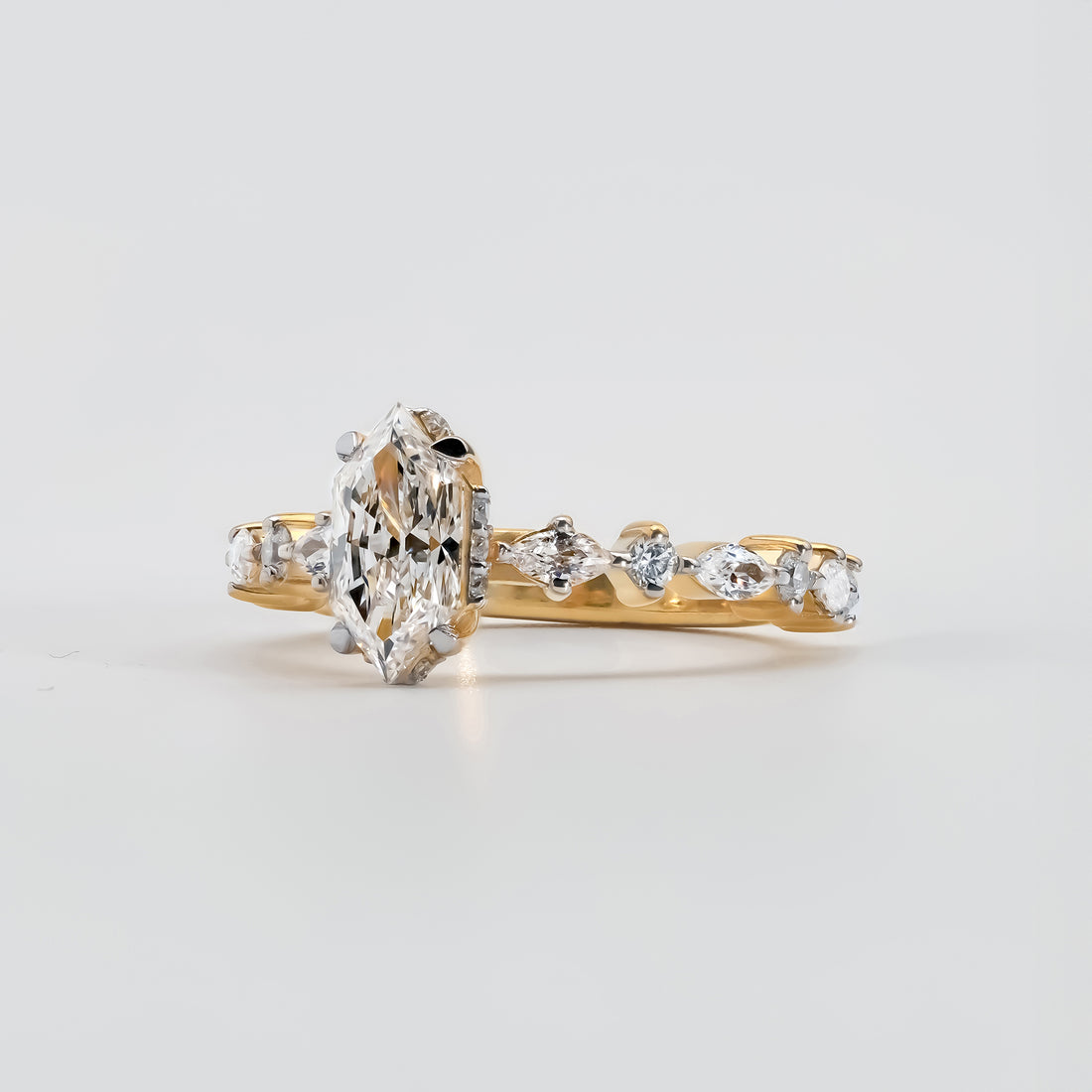 The band is adorned with alternating marquise and round-cut accent diamonds, creating an intricate and elegant pattern that enhances the ring’s brilliance and luxury.