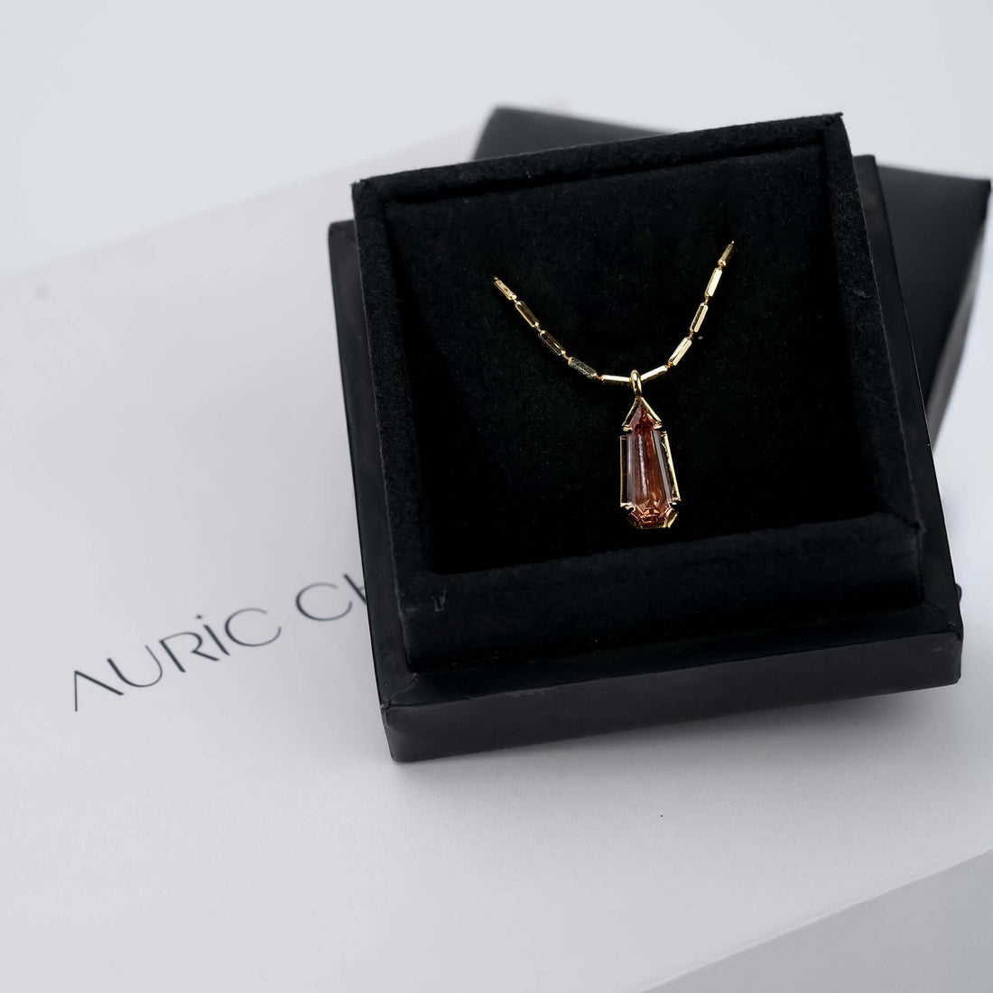 A graceful gold necklace adorned with a soft pink gemstone pendant that glimmers beautifully, symbolizing warmth and refined femininity.