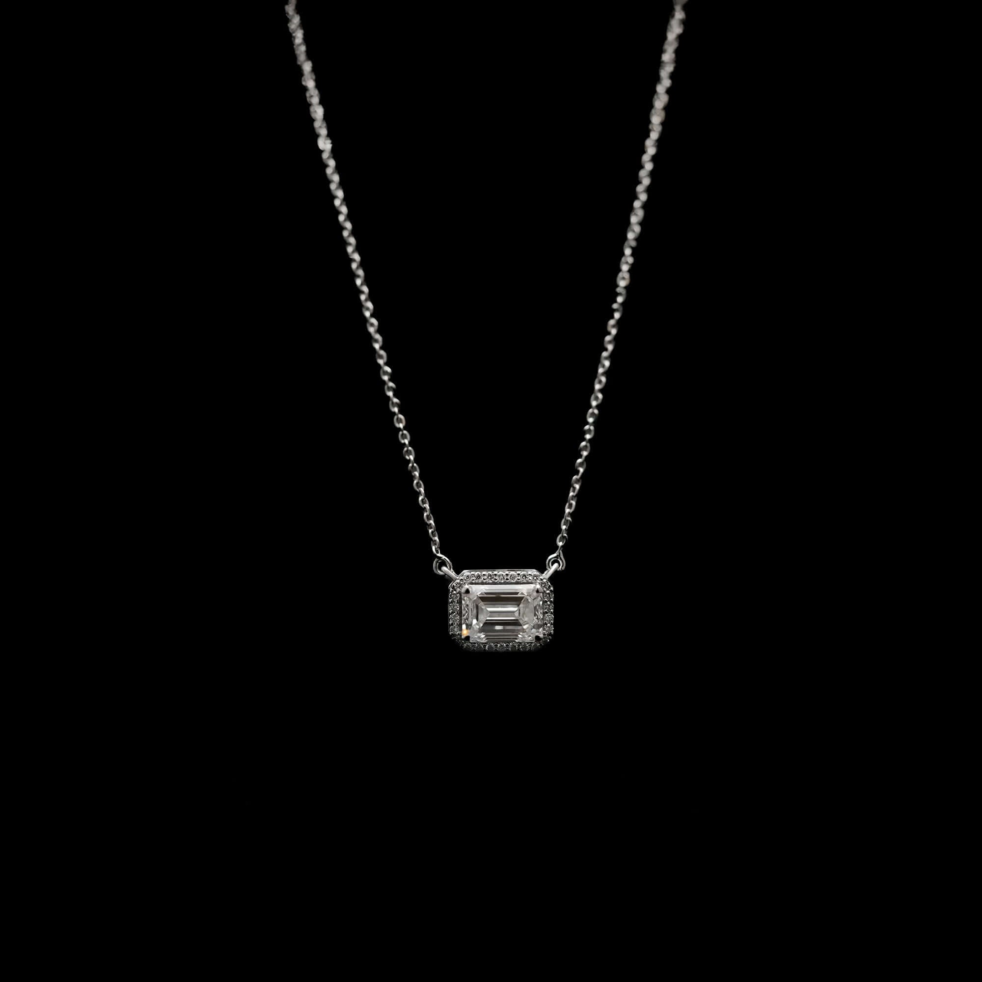 Silver diamond pendant necklace with emerald-cut center stone and halo setting, displayed on model for a refined and classic presentation.