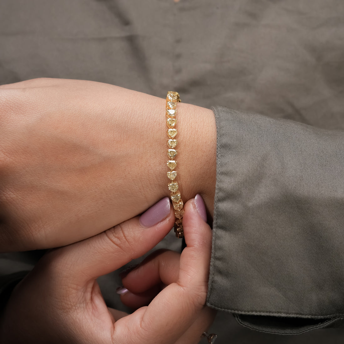 A radiant gold bracelet lined with sparkling heart-cut diamonds, capturing light beautifully in a delicate display of brilliance and craftsmanship.