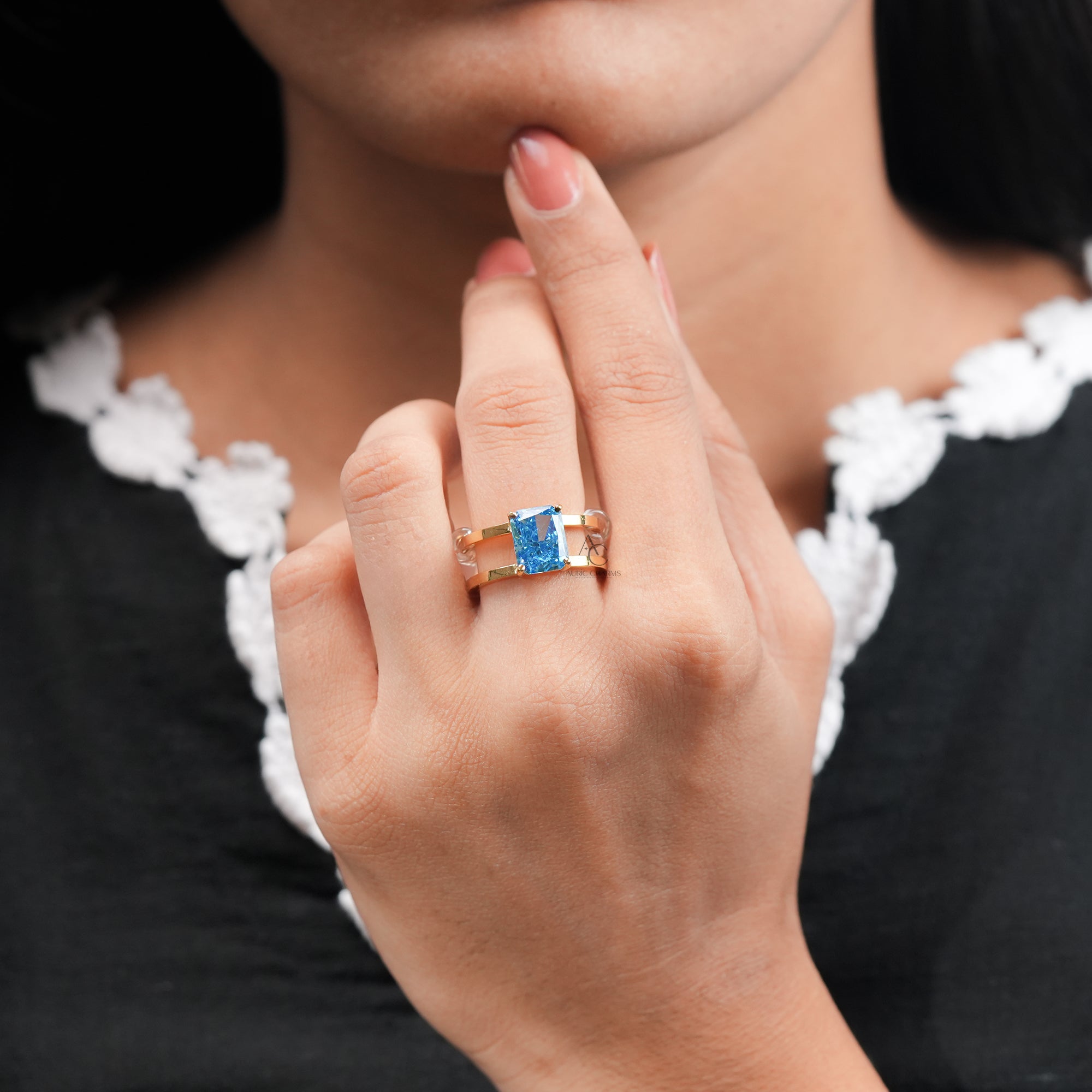 Elegant gold engagement ring with rectangular-cut blue gemstone.