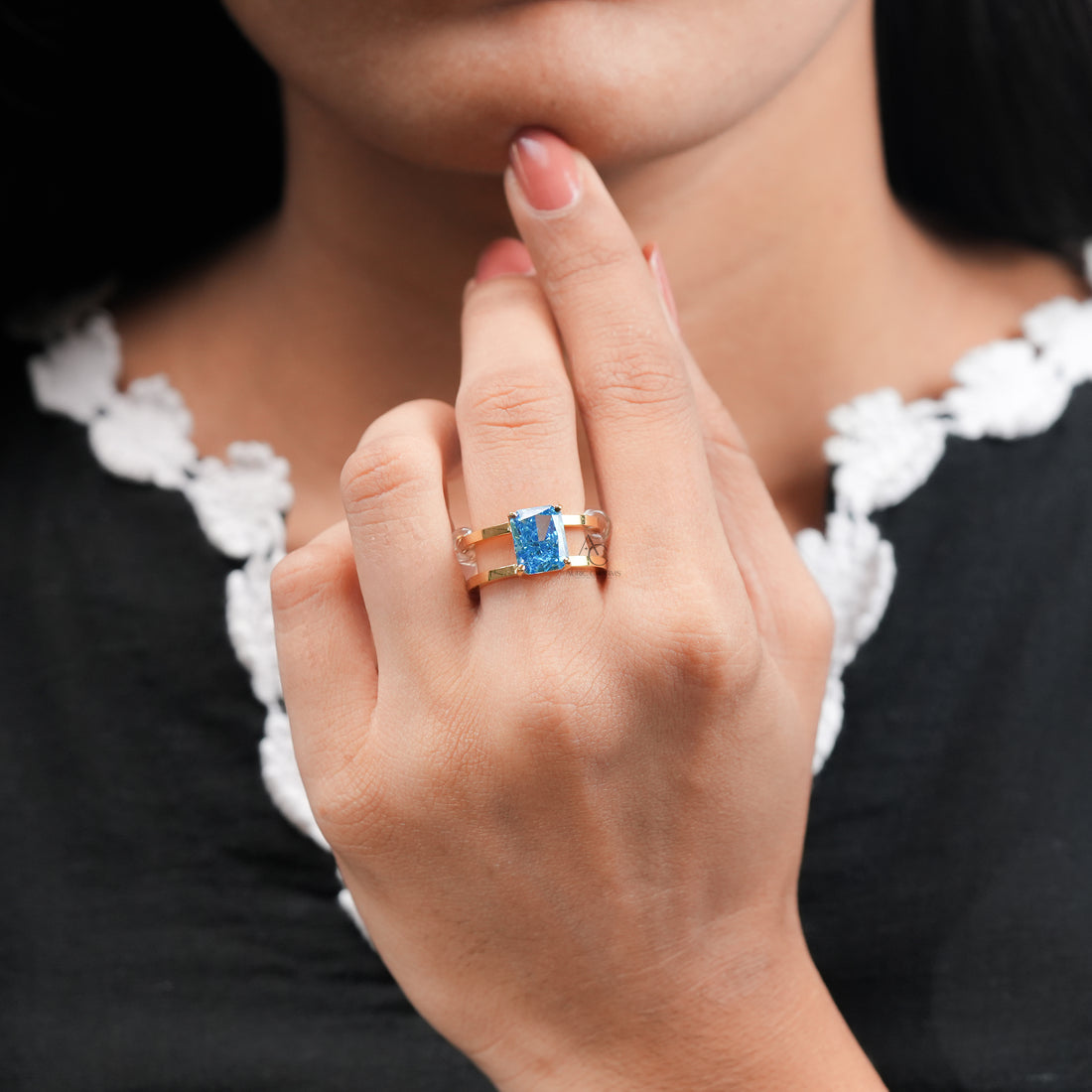 Elegant gold engagement ring with rectangular-cut blue gemstone.