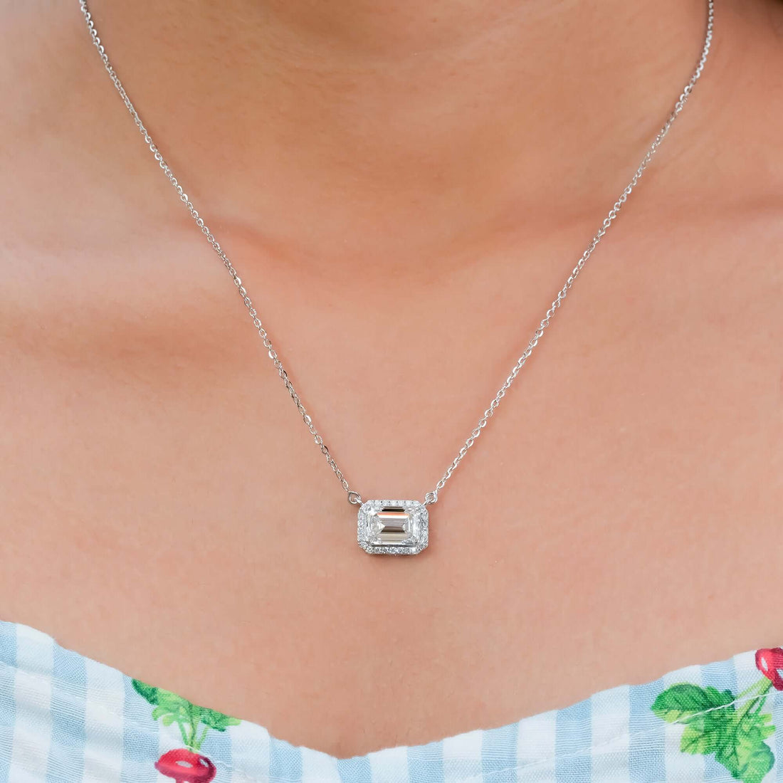 Diamond pendant necklace in silver with an emerald-cut center stone and halo setting, offering a sophisticated and elegant jewelry design for everyday or special occasions.