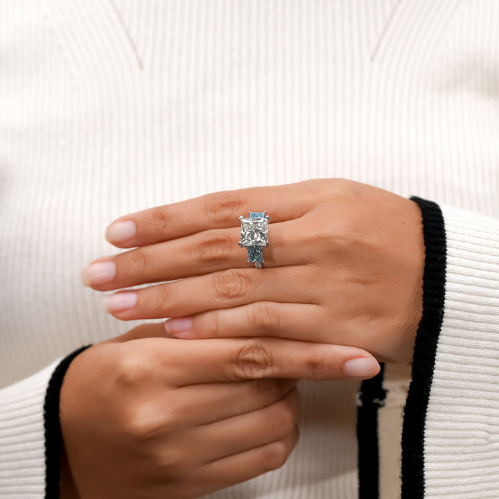 Modern diamond engagement ring featuring princess white and blue diamonds, crafted in white gold.