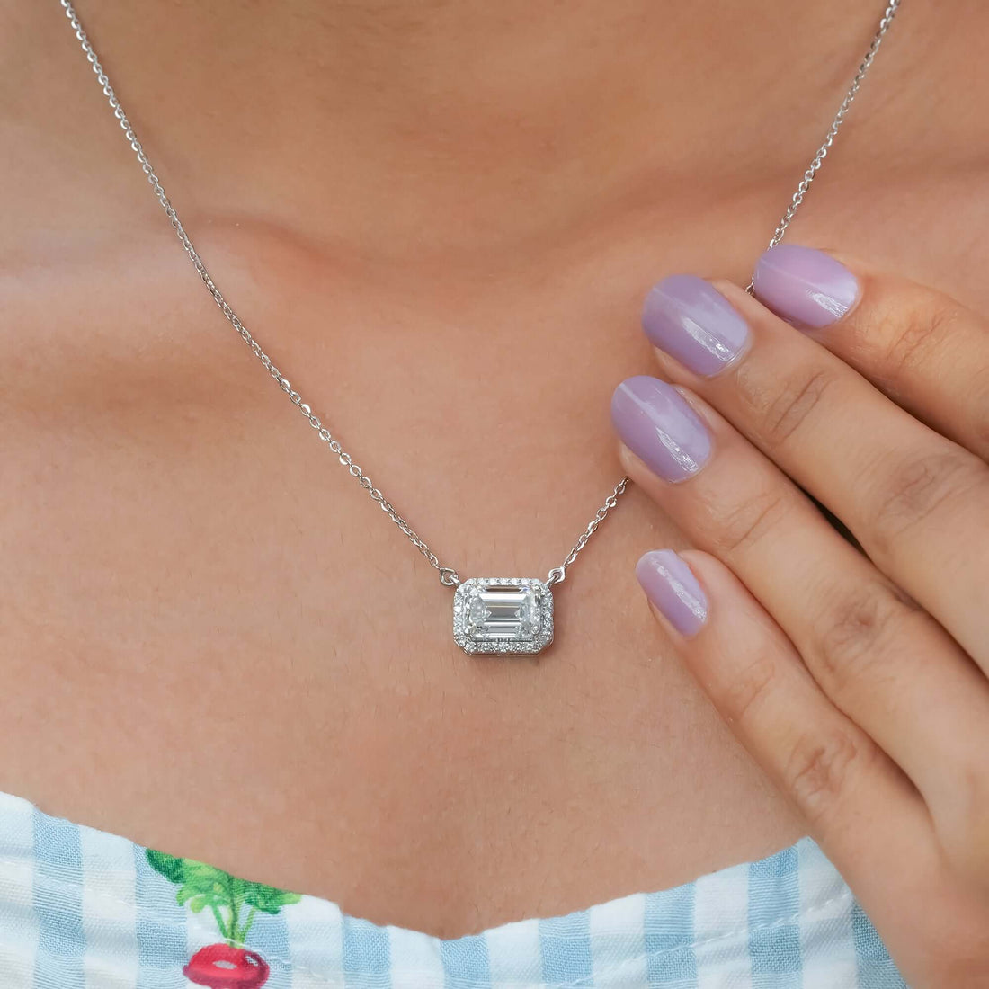 A sparkling halo diamond pendant necklace with an emerald-cut centerpiece, adding a touch of radiant beauty and sophistication to the neckline