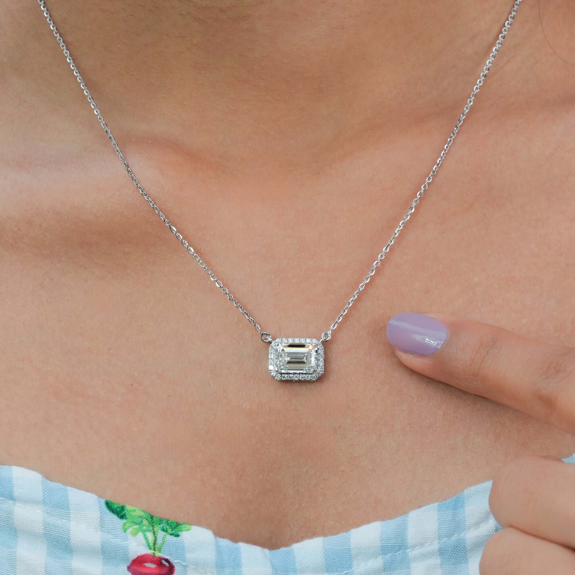 An exquisite halo pendant necklace crafted in silver, featuring an emerald-cut diamond framed by smaller brilliant stones for a refined, luxurious appeal.
