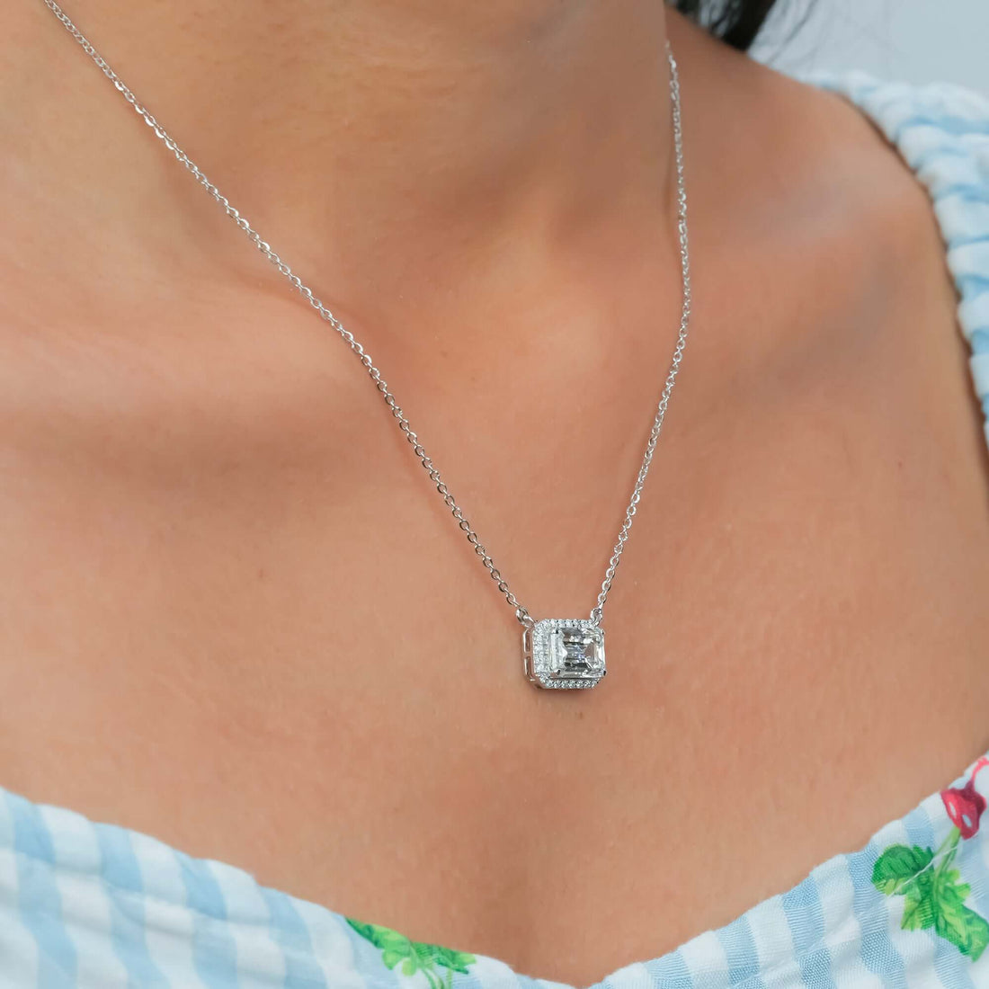 A glimmering diamond halo pendant rests gracefully on the neckline, capturing the perfect blend of elegance, simplicity, and timeless charm.
