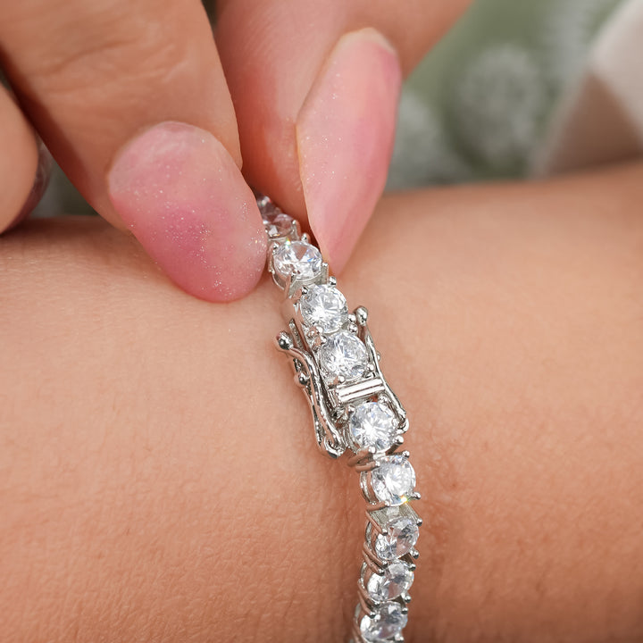 A sparkling diamond tennis bracelet adorns the wrist, its brilliant stones catching the light
