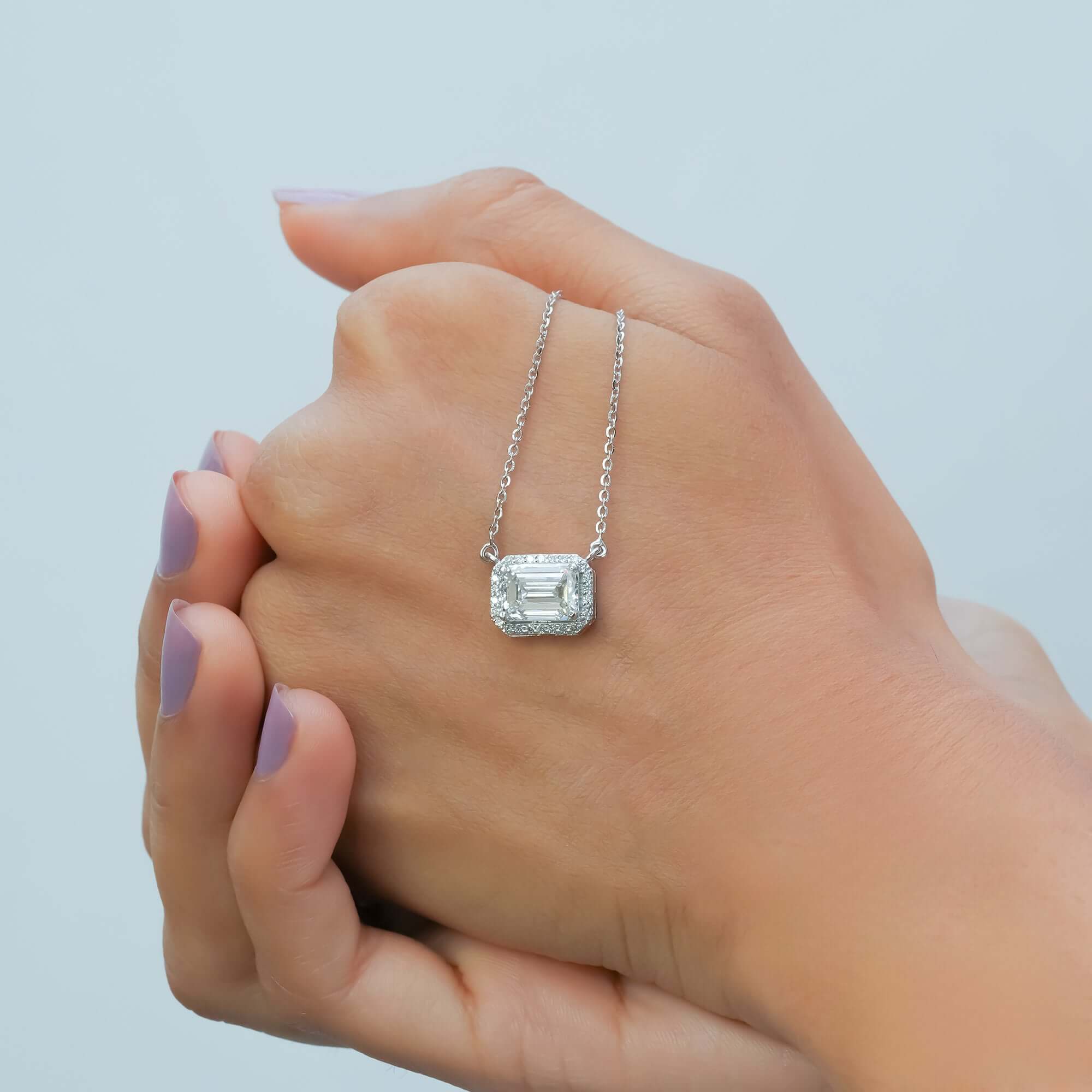 A sleek silver necklace with a halo diamond pendant accentuates the neckline, blending minimal design with classic sophistication.