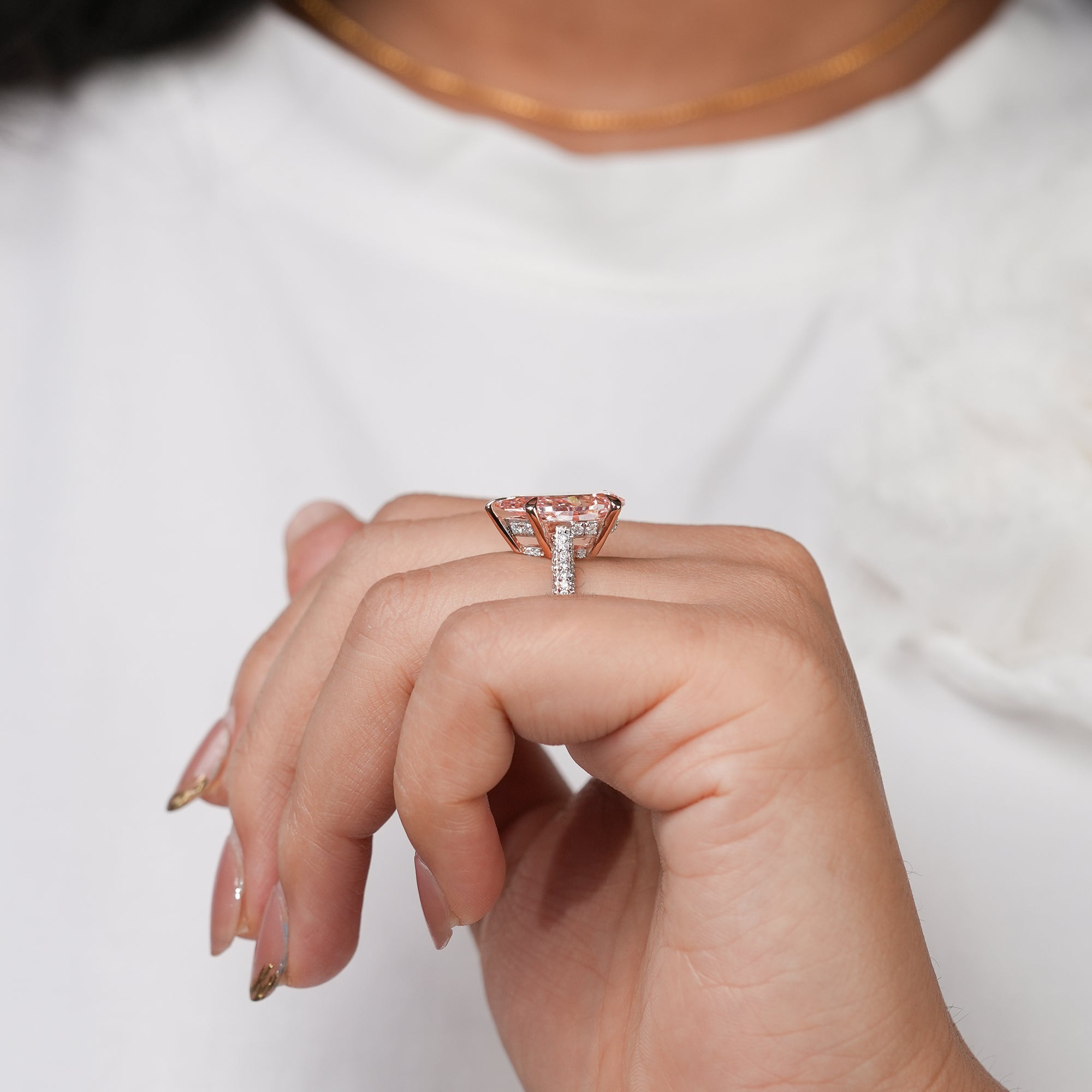 A stunning rose gold ring centered with a brilliant pear-shaped pink gemstone that glows warmly, complemented by a glittering diamond band for a luxurious and captivating look.