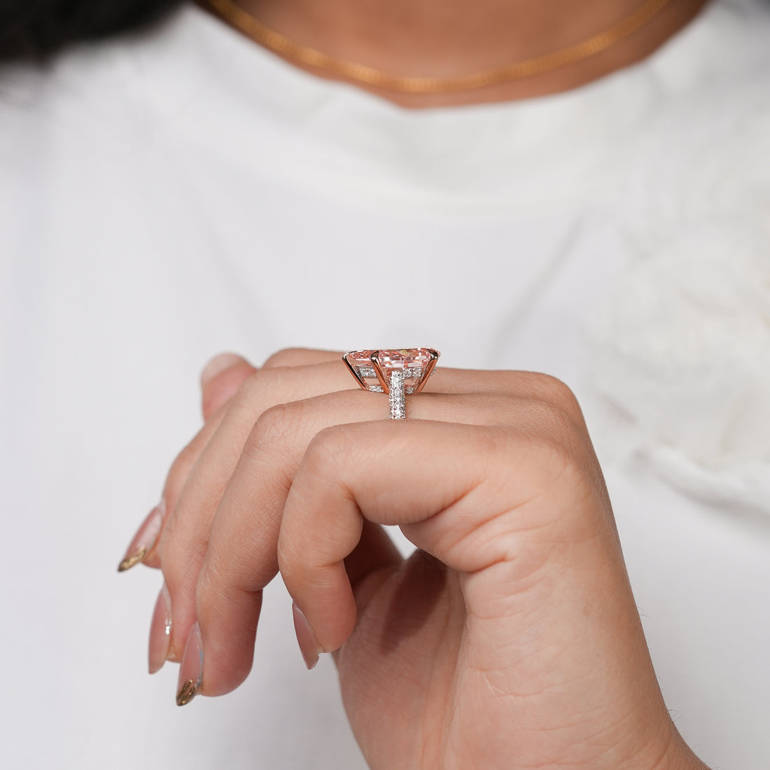 A stunning rose gold ring centered with a brilliant pear-shaped pink gemstone that glows warmly, complemented by a glittering diamond band for a luxurious and captivating look.