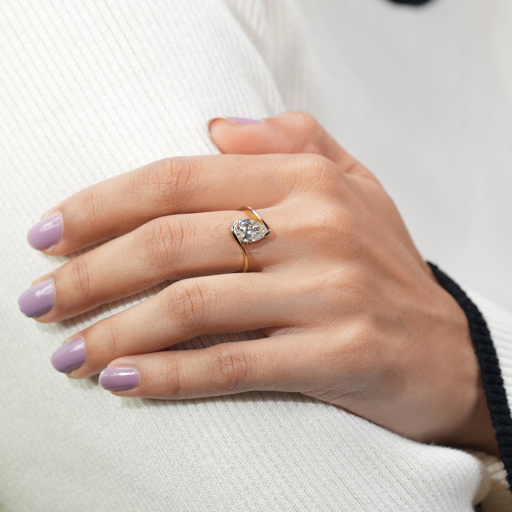 An elegant gold ring featuring a pear-cut diamond in an asymmetrical, open setting