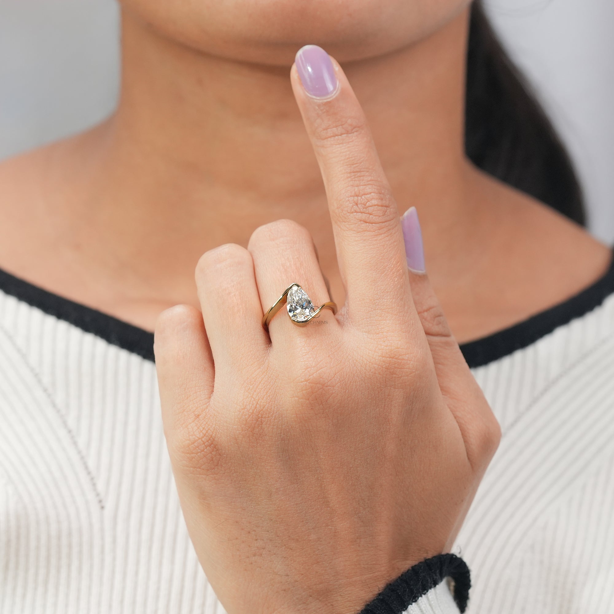 Modern pear-shaped diamond engagement ring with a sculptural yellow gold band.