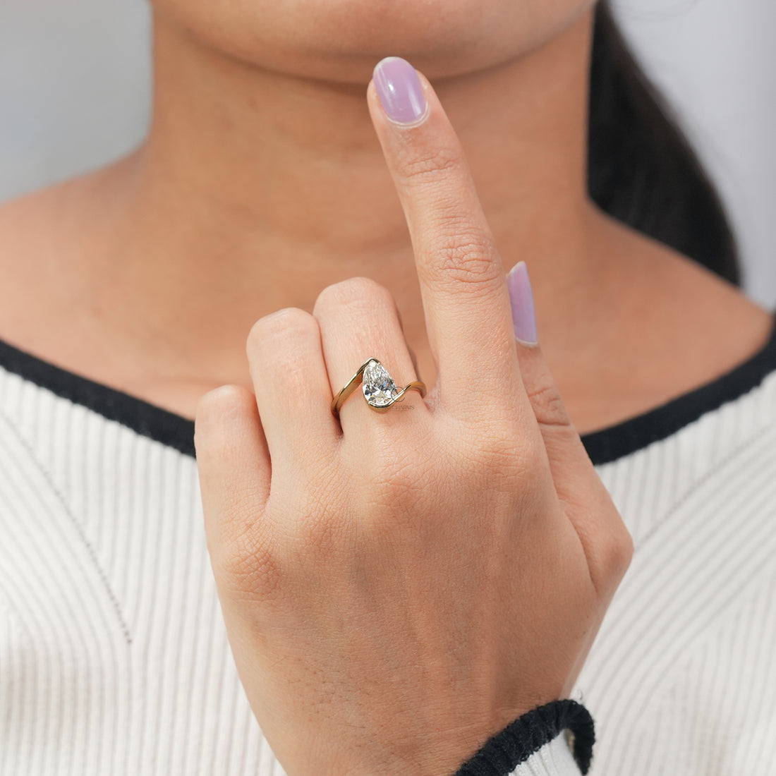 Modern pear-shaped diamond engagement ring with a sculptural yellow gold band.