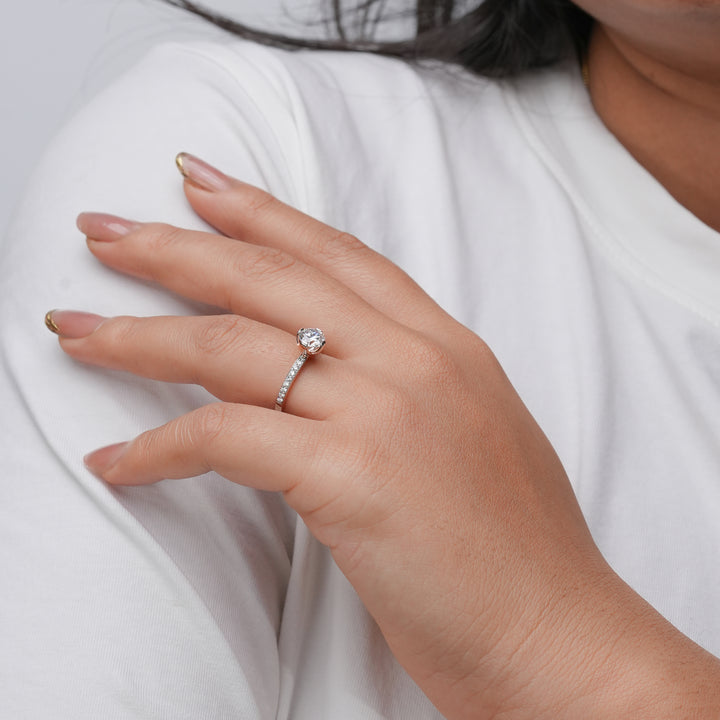 Sophisticated white gold engagement ring with a central round diamond and delicately set pavé diamonds along the band.