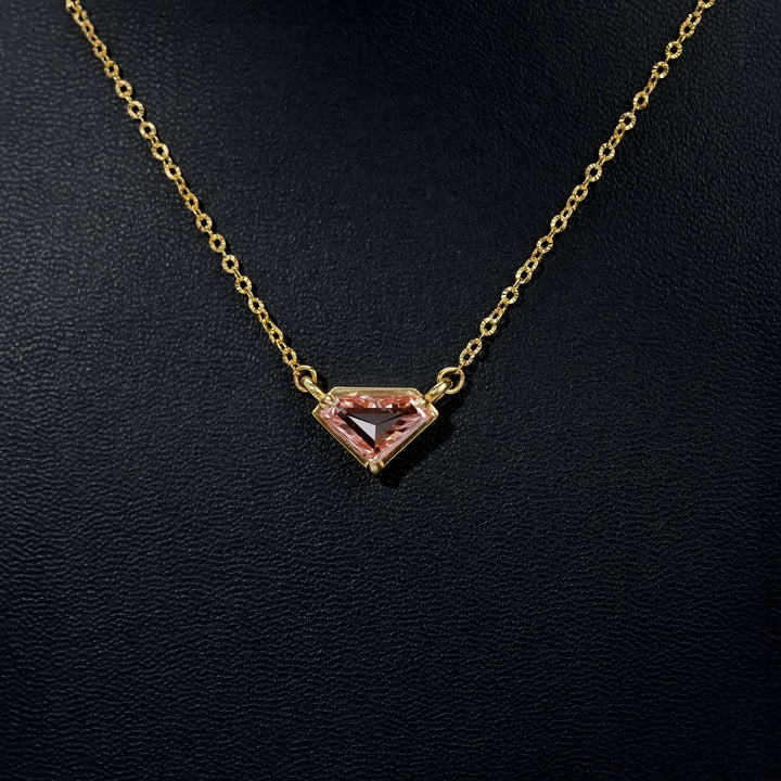 A delicate gold necklace with a pink kite-cut gemstone pendant, radiating a refined and contemporary charm.
