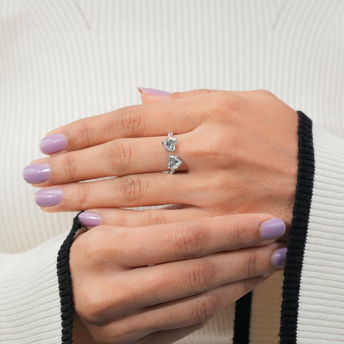 Double heart engagement ring with clear gemstones in silver setting.