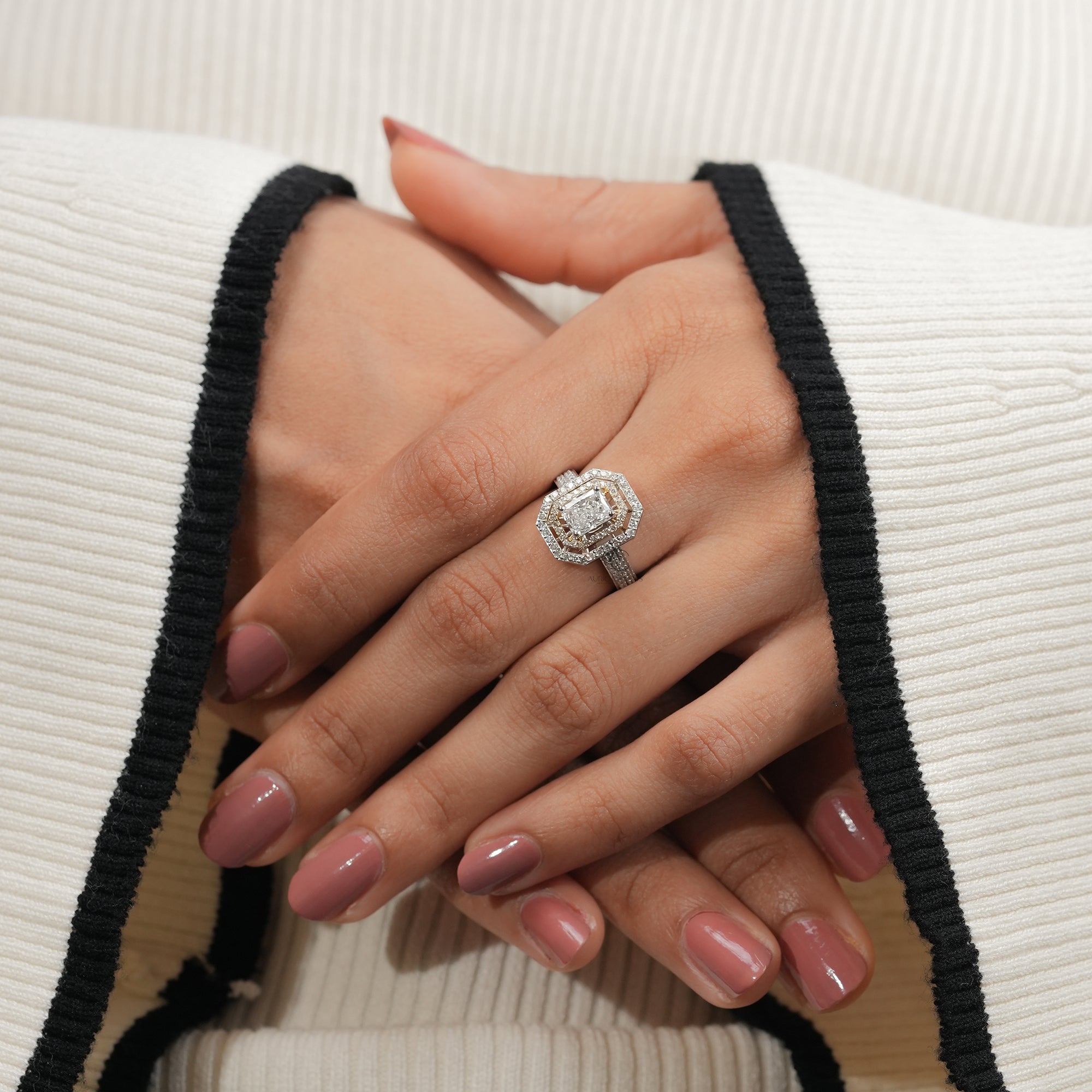 engagement ring featuring a large radiant-cut diamond framed by a double halo of smaller diamonds and a pavé-set band