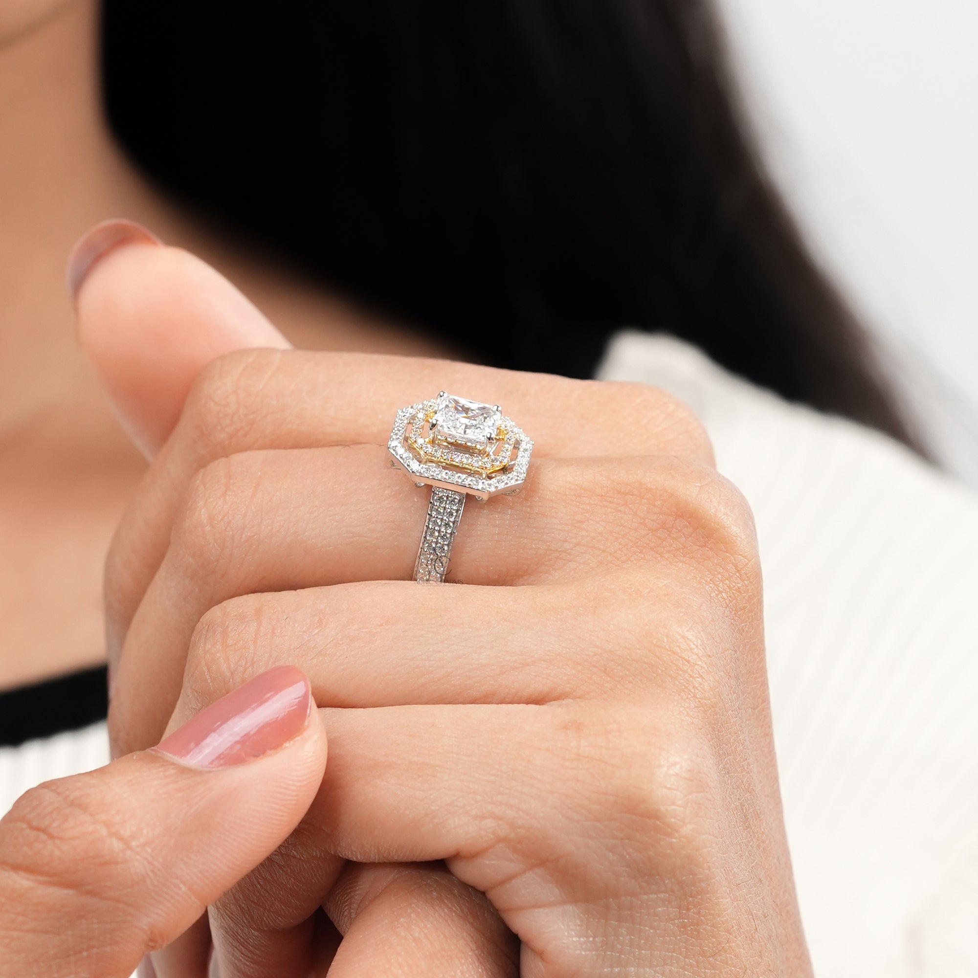 An ornate diamond ring showcasing a rectangular radiant-cut center stone, surrounded by two halos of smaller diamonds