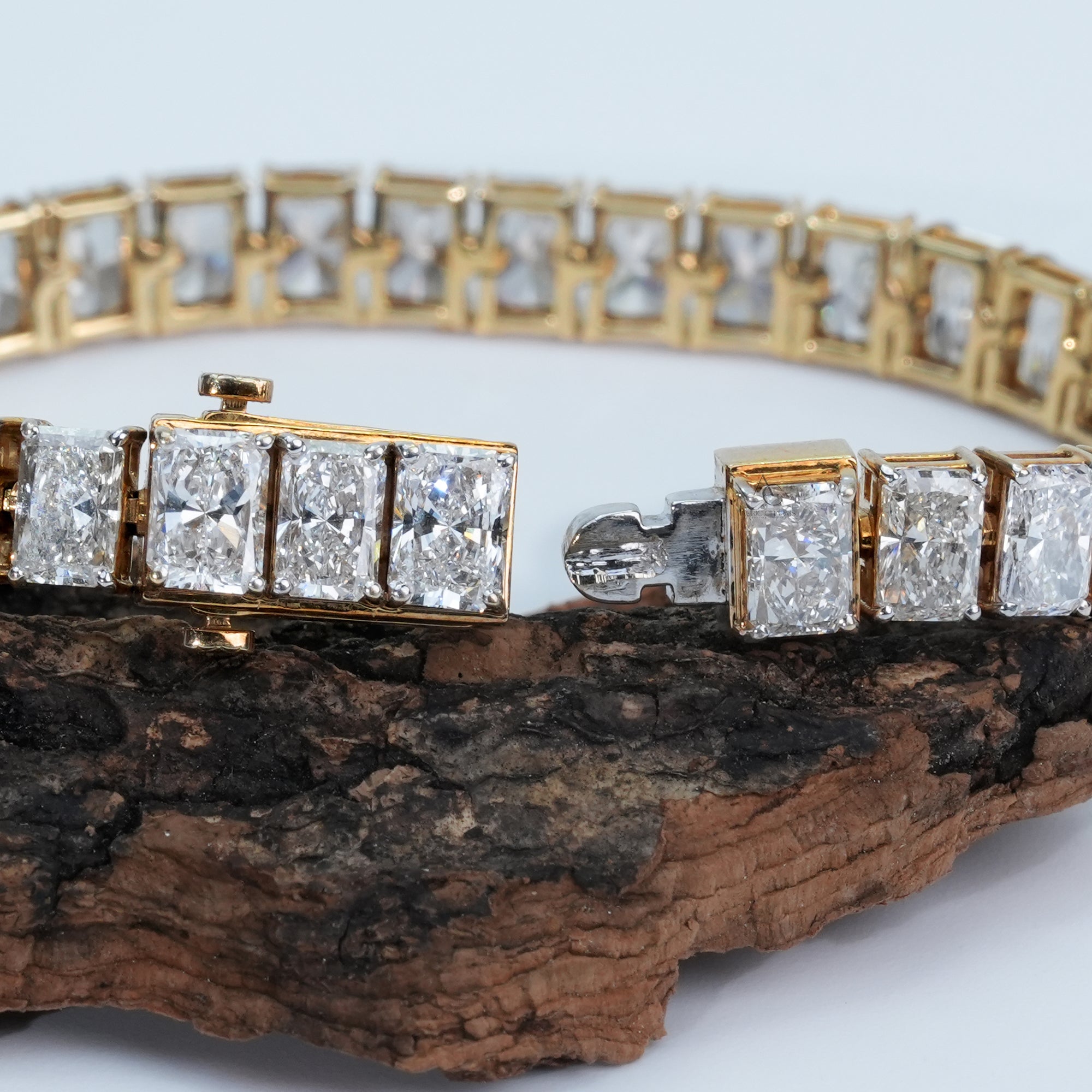 A stunning gold bracelet encircled with perfectly cut radiant diamonds that sparkle with every angle, resting on a soft white textured surface for a modern, luxurious look.