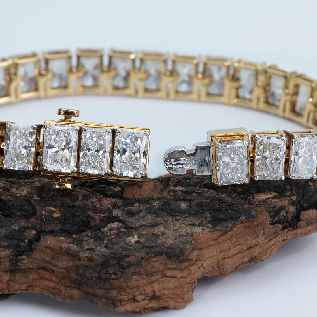 A stunning gold bracelet encircled with perfectly cut radiant diamonds that sparkle with every angle, resting on a soft white textured surface for a modern, luxurious look.