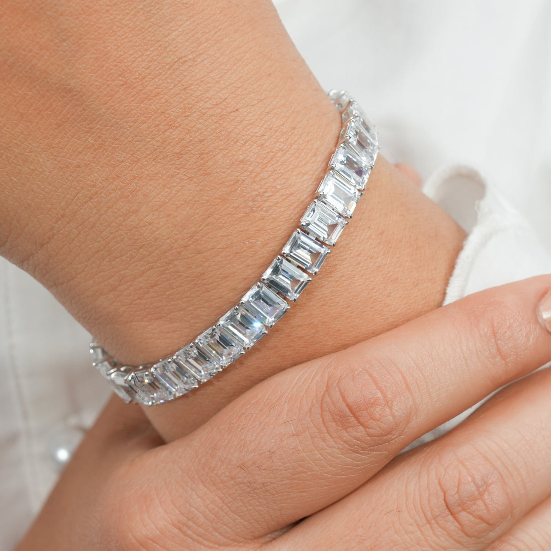 A refined silver bracelet adorned with emerald-cut diamonds, gracefully encircling the wrist and radiating understated elegance.