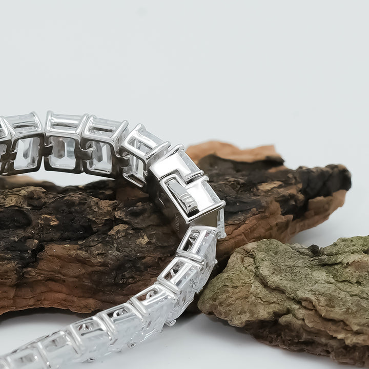 A contemporary silver bracelet with emerald-cut stones, sleek and elegant, worn over a white cuff sleeve.