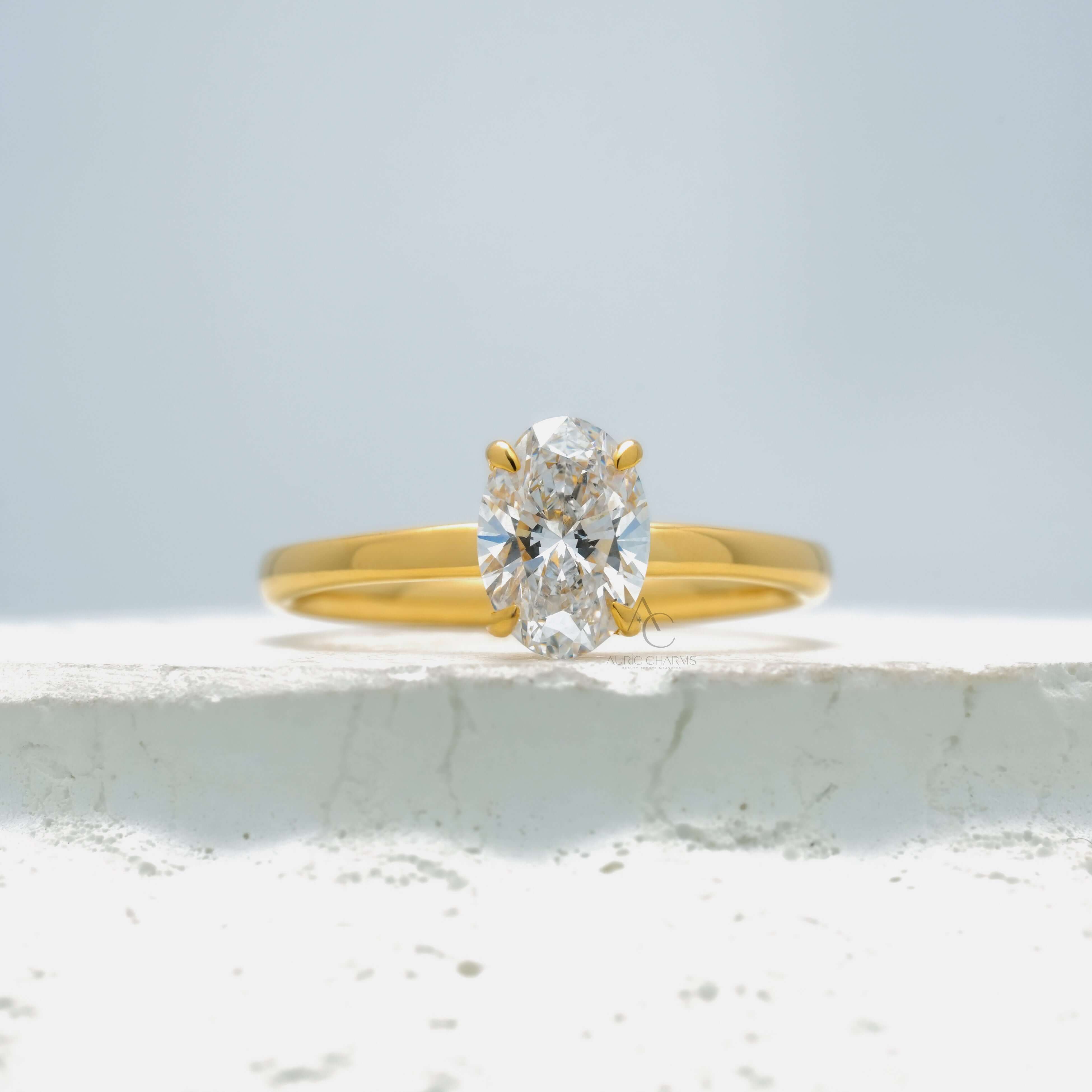 Oval-cut solitaire diamond ring with a sleek metal band on a reflective surface.